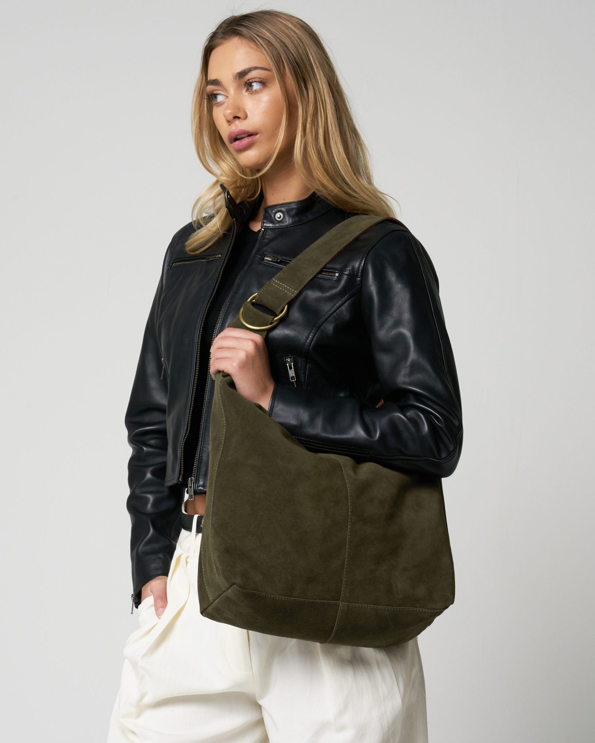 Woman holding a green leather bag against a plain background