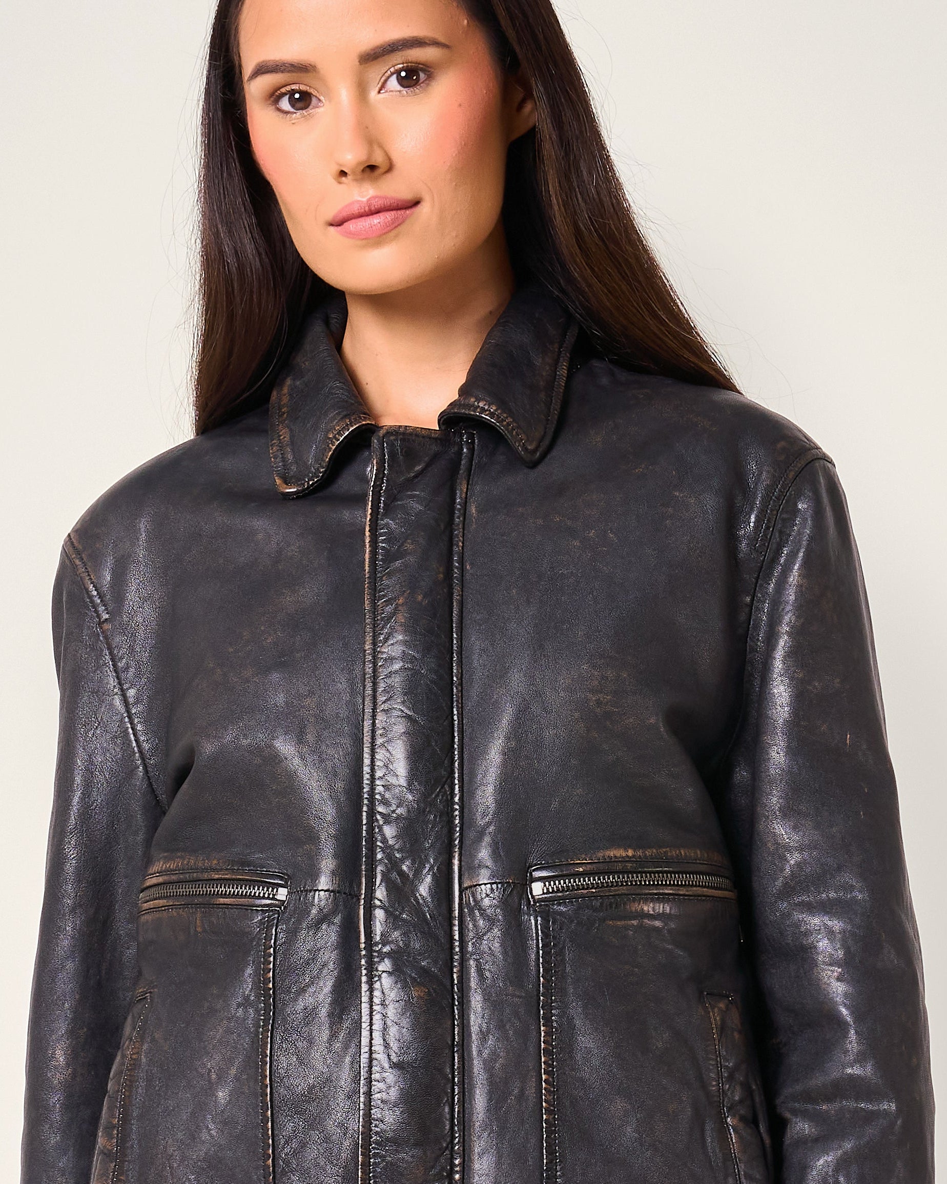 Woman wearing a black leather jacket against a plain background
