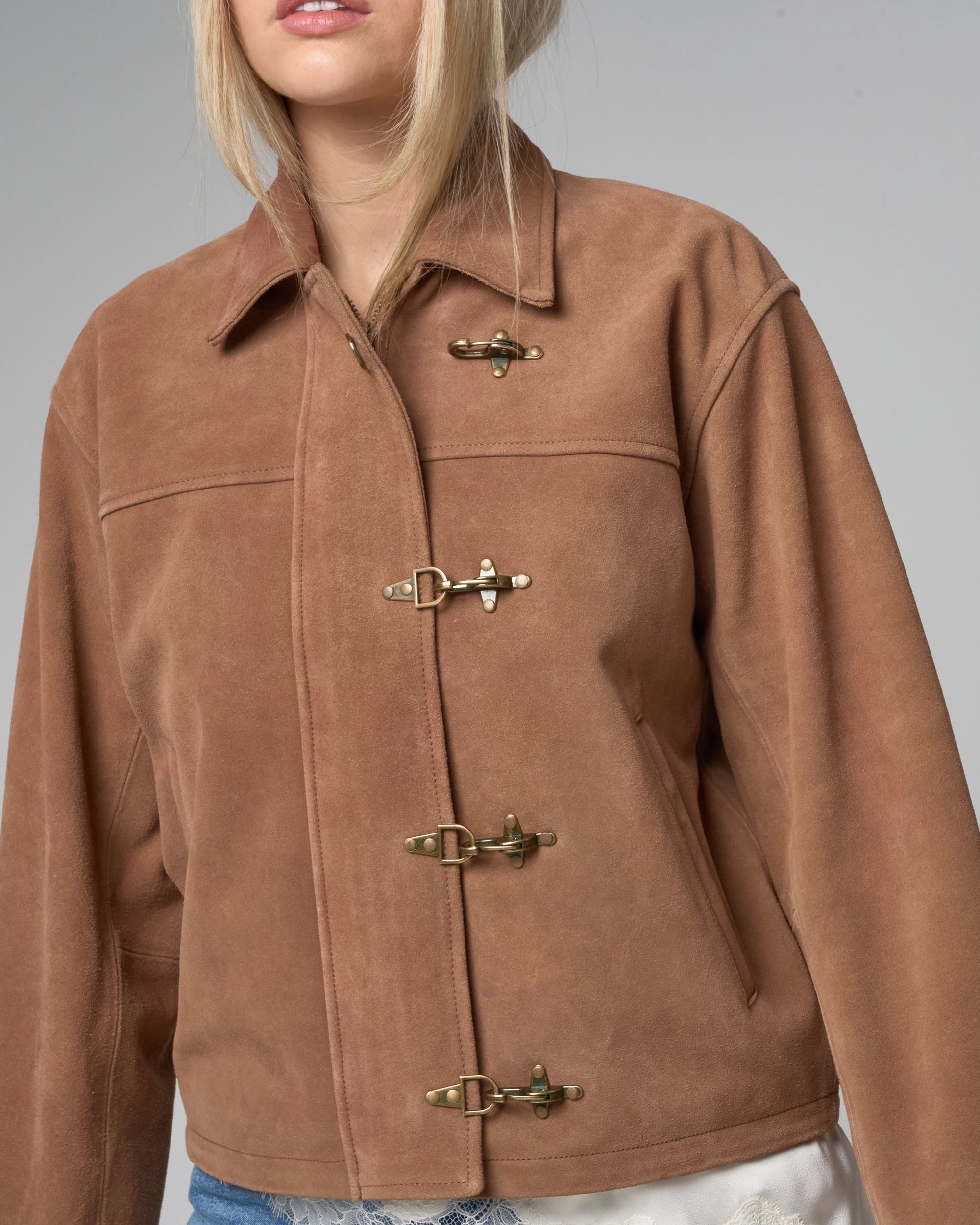 Close up detail of tan suede jacket by Barneys Originals - featuring central zipline. This image shows what the jacket looks like closed - with the clasps fastened over the zipline.