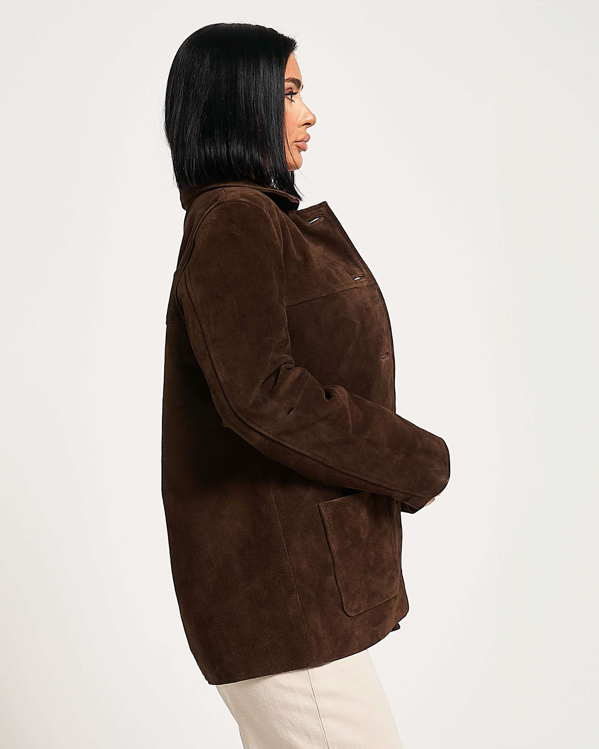 Person wearing a brown suede jacket on a white background facing to the side.