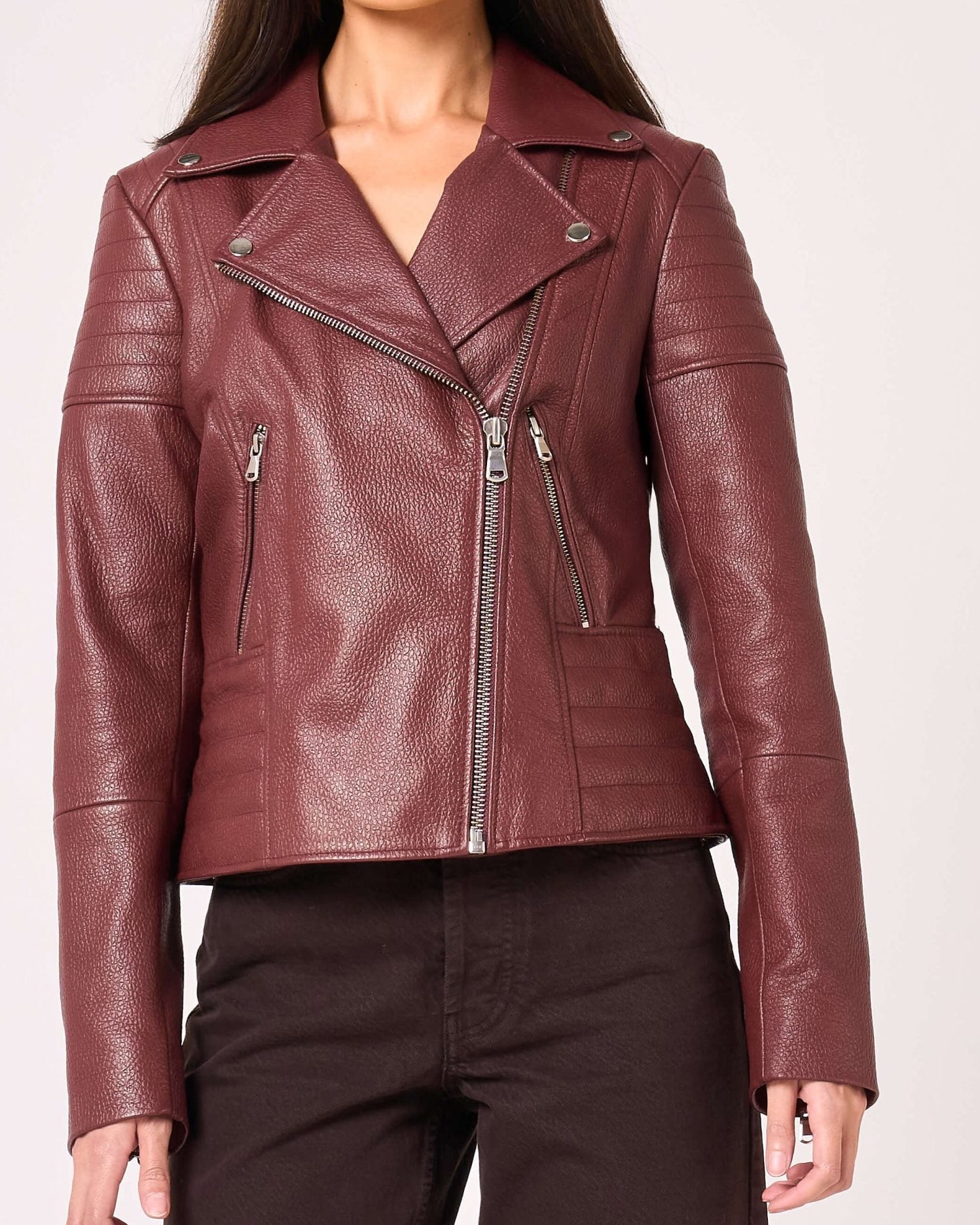 Woman wearing a burgundy leather jacket on a white background