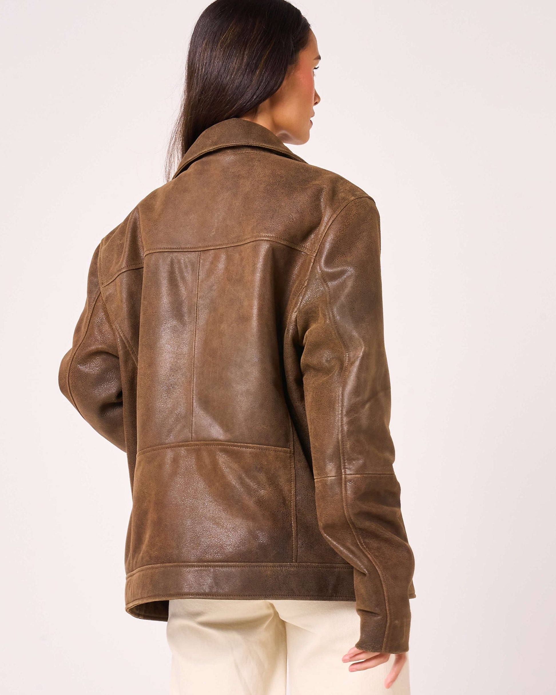 Brown leather jacket worn by a person on a white background