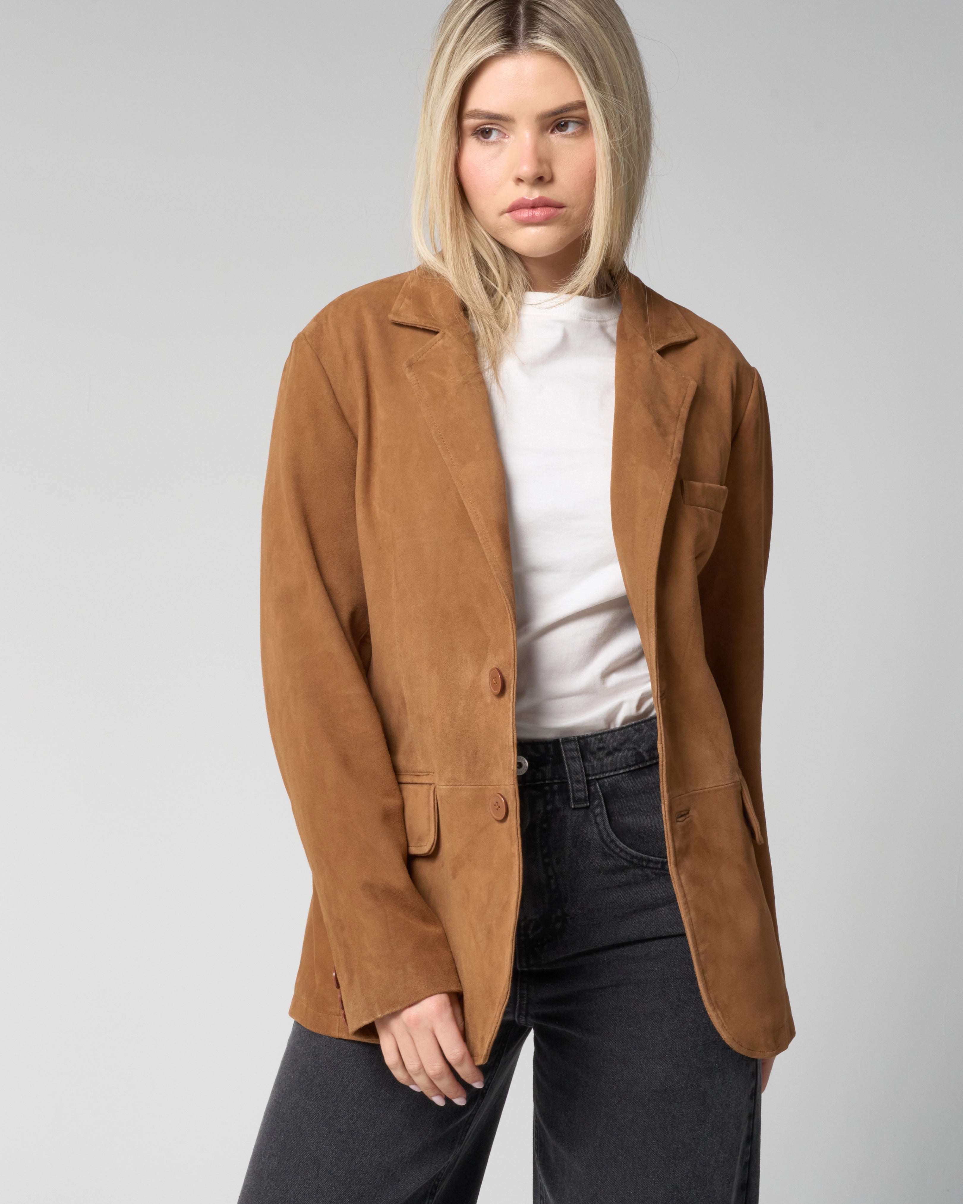 Woman wears a tan blazer made of real suede, with two buttons unfastened.