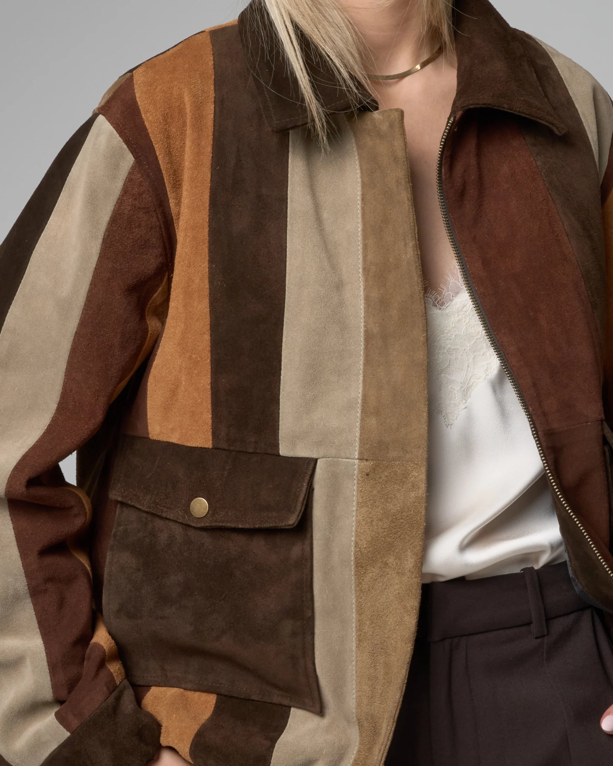Close up detail of suede jacket for women - striped pattern suede panels in beige, tan and brown.