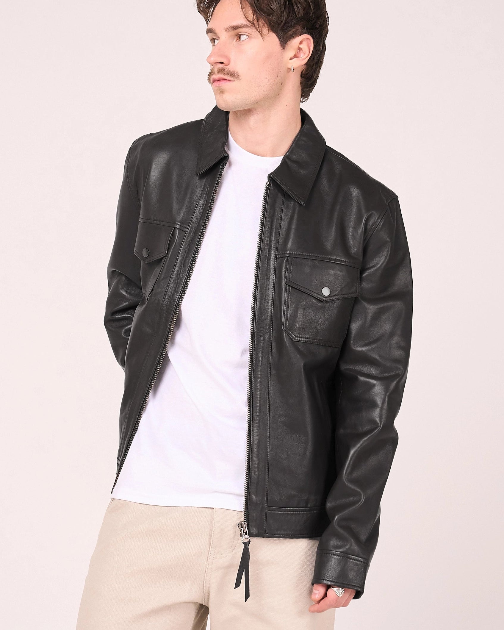 Man wearing a black leather jacket in a photo studio. 