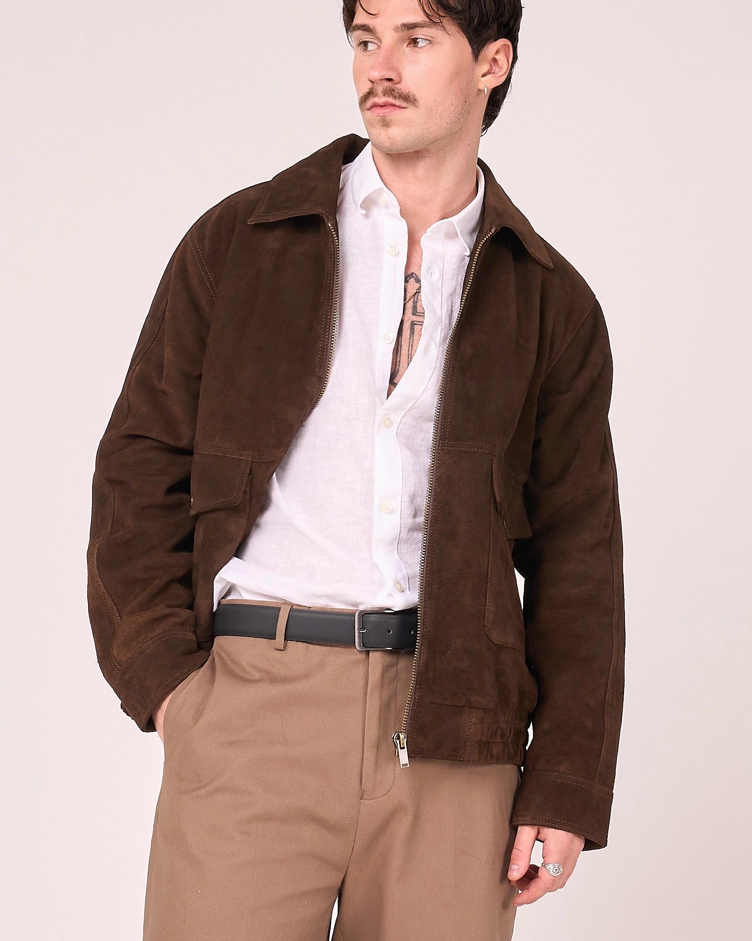 Image shows a man wearing the brown buffalo suede jacket unzipped to reveal a crisp white shirt below.
