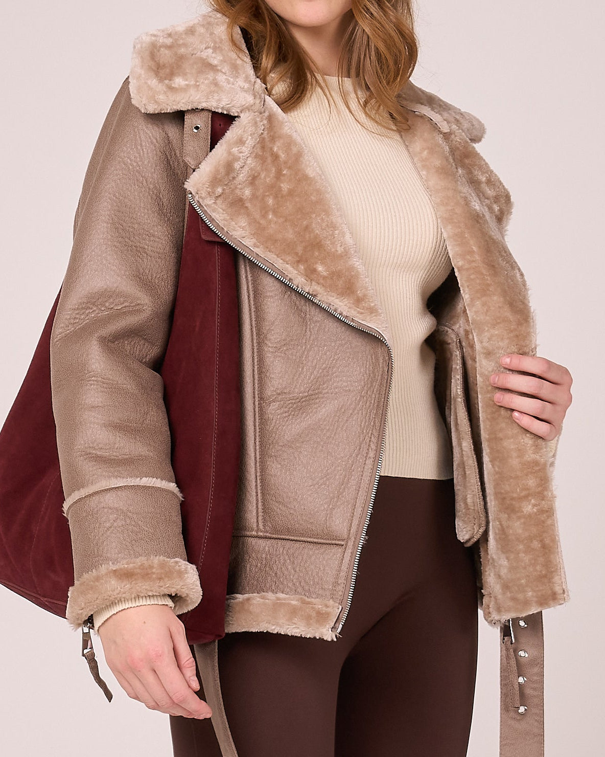 Person wearing a brown faux shearling jacket, with asymmetric zipline and classic aviator vibes.