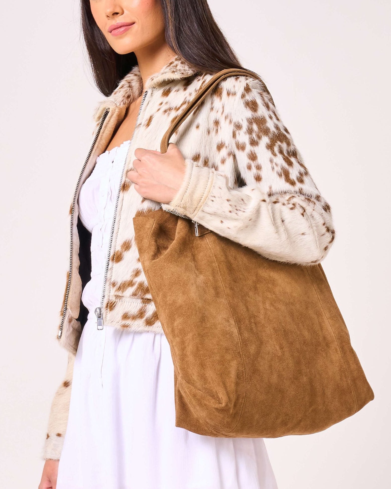 Woman holding a brown suede bag against a white background