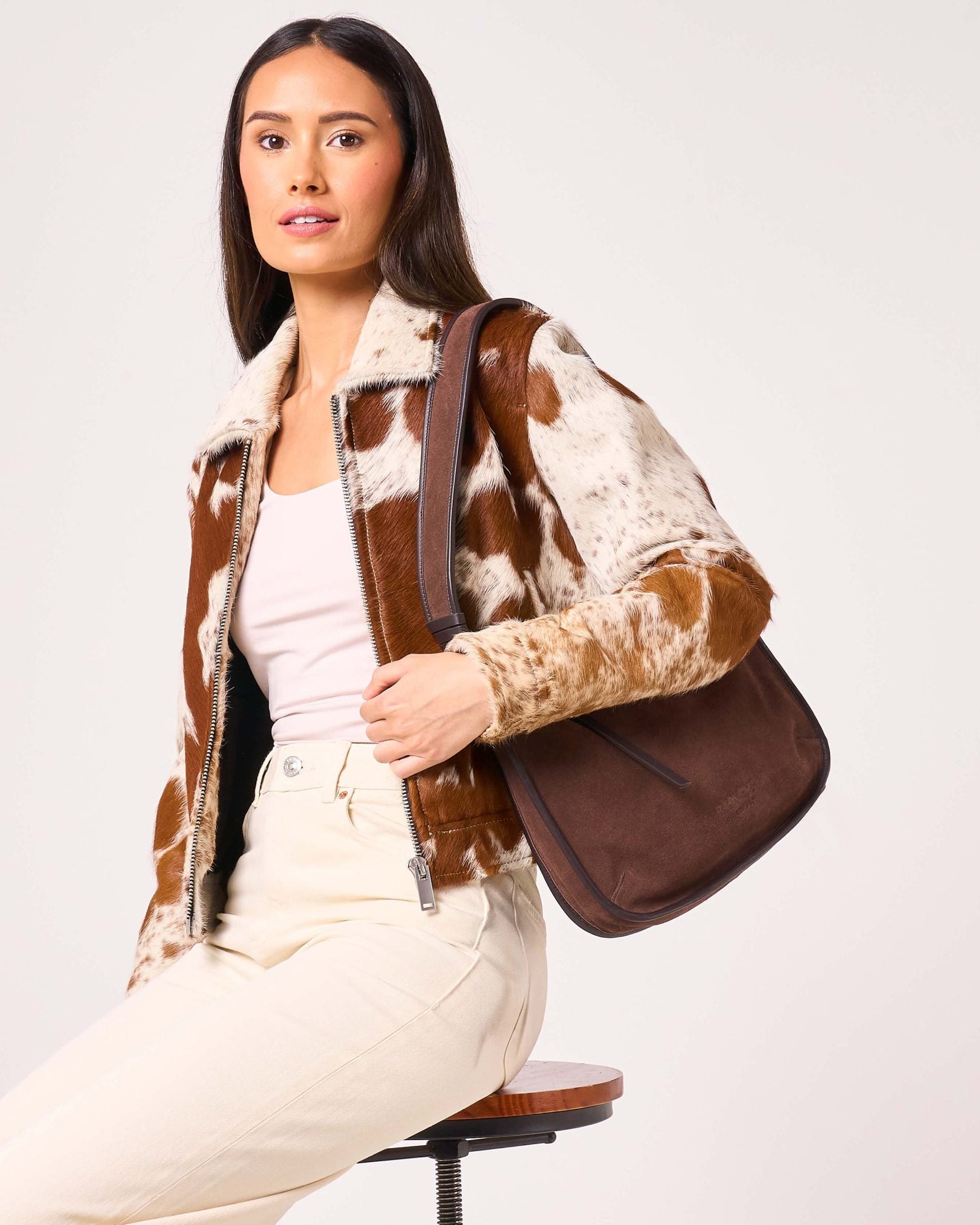 Woman holding a brown leather bag against a white background