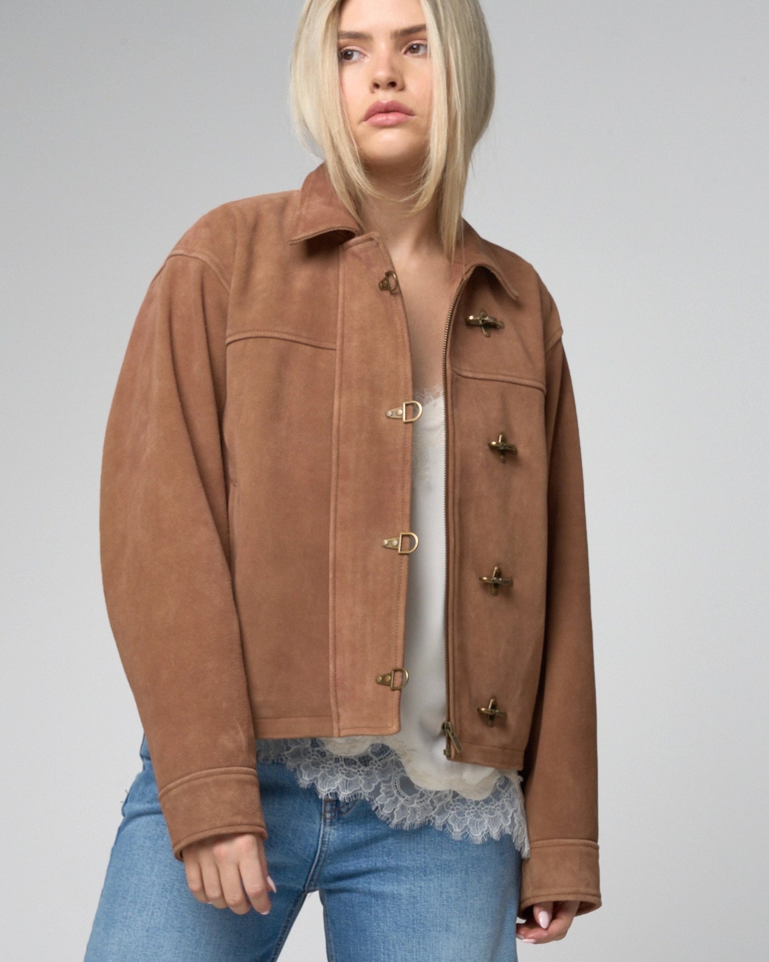 Image of woman wearing a tan suede jacket, open and unzipped.