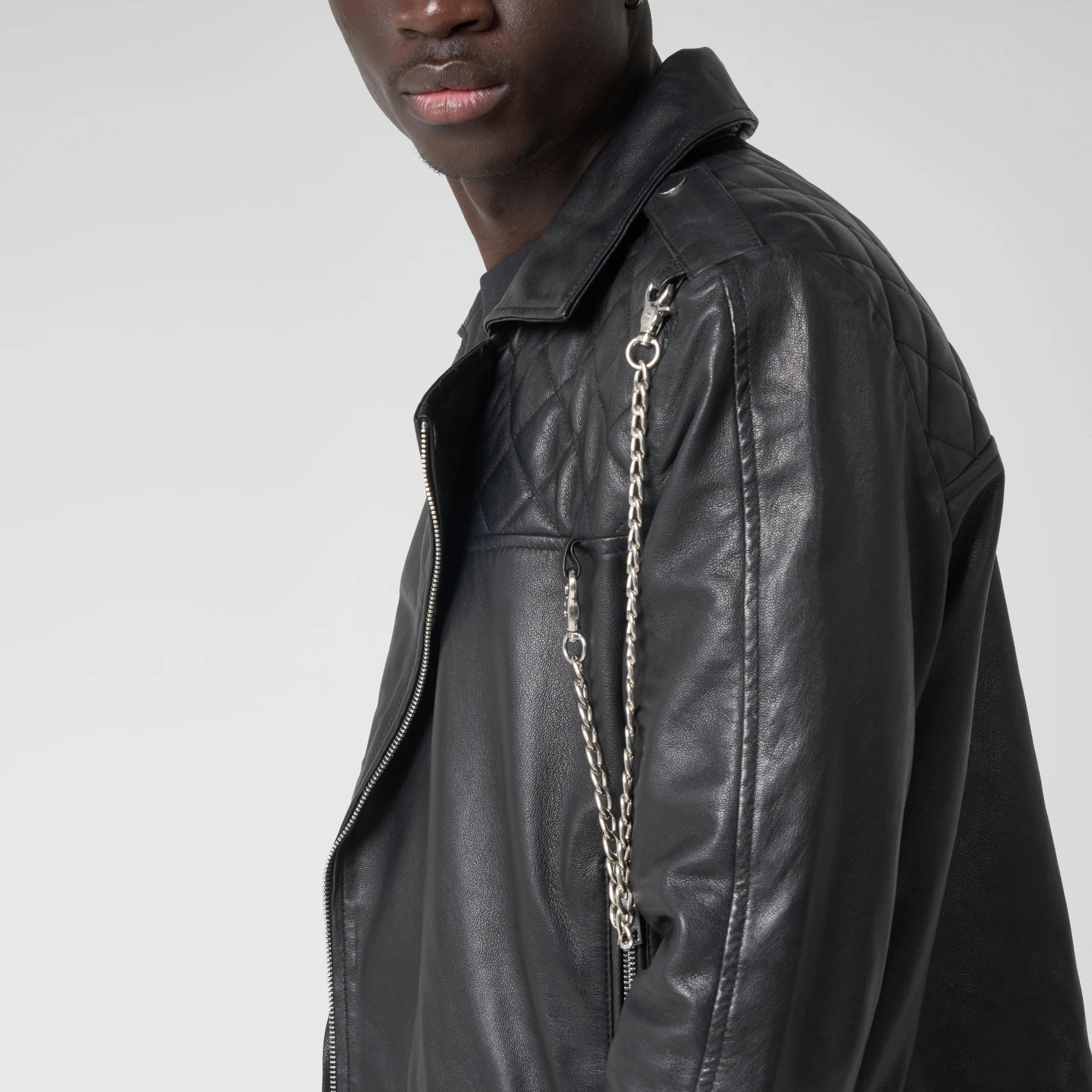 Black leather jacket with chain detail on a plain background