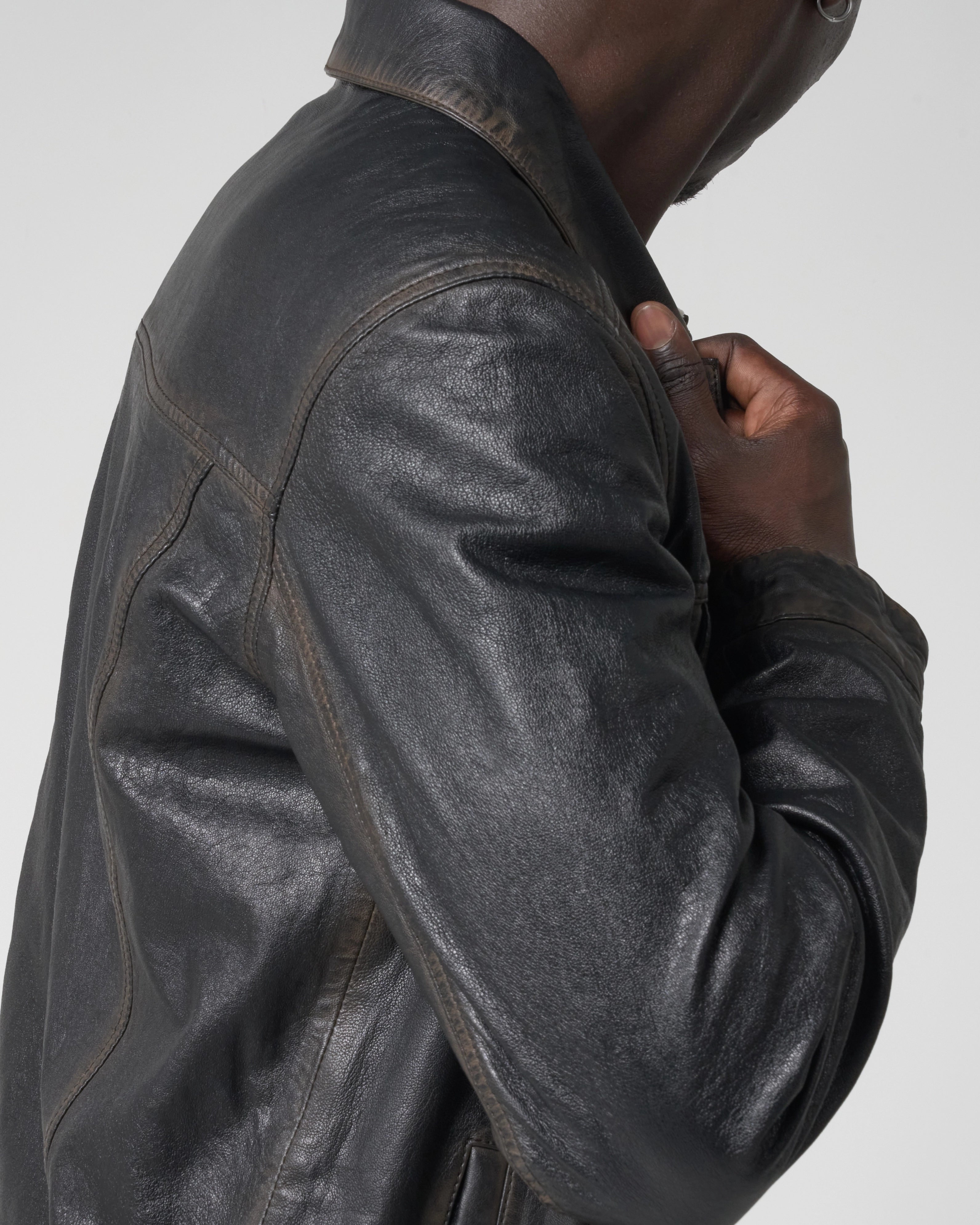 Image shows man turning away from camera whilst wearing the black leather jacket. The leather has a grainy texture with washed detail.