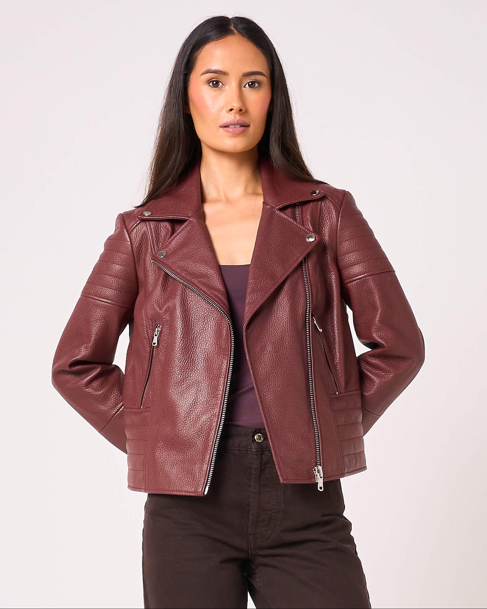 Woman wearing a maroon leather jacket on a white background