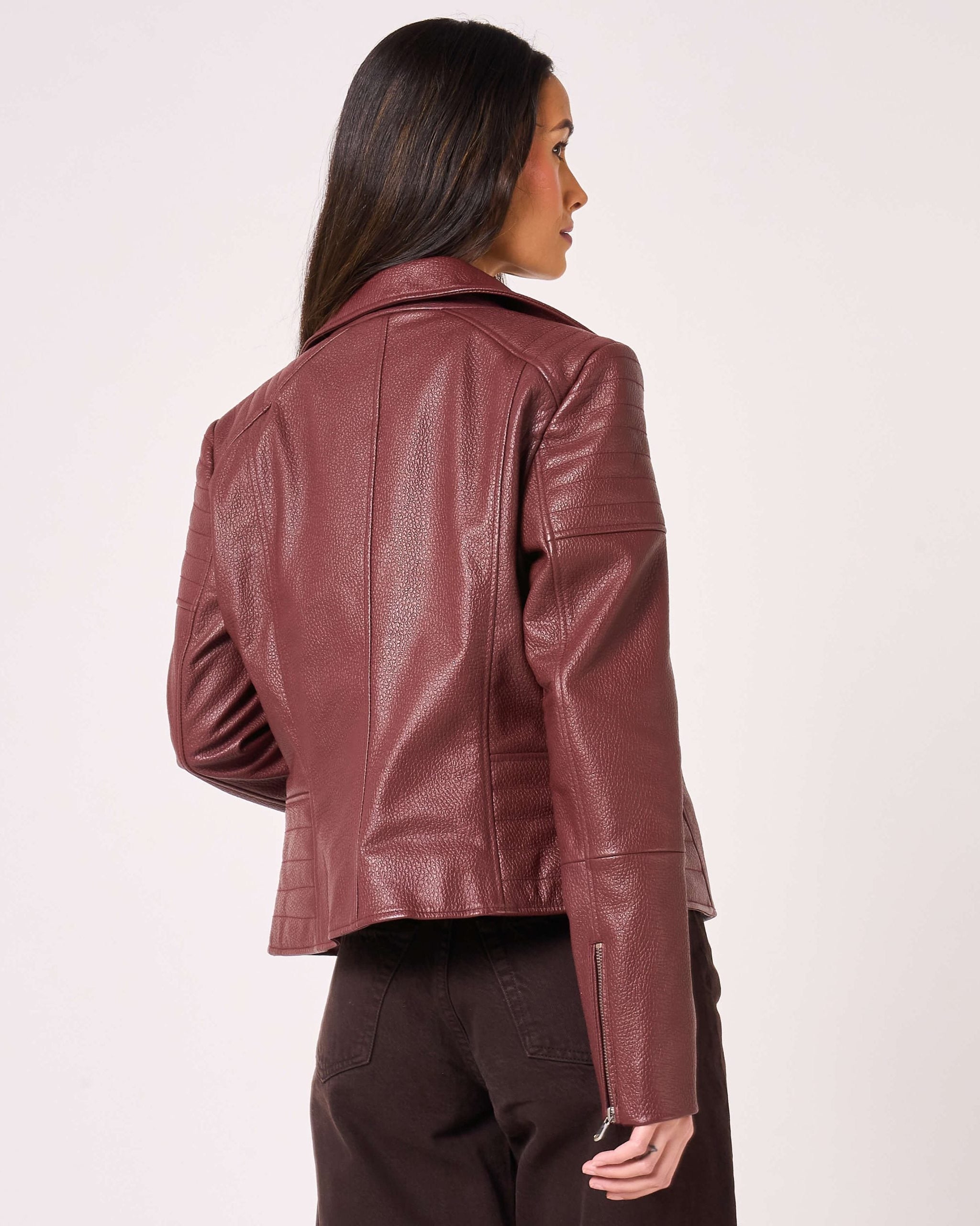 Back of burgundy coloured leather biker jacket. The back of the sleeves have small functional zippers.