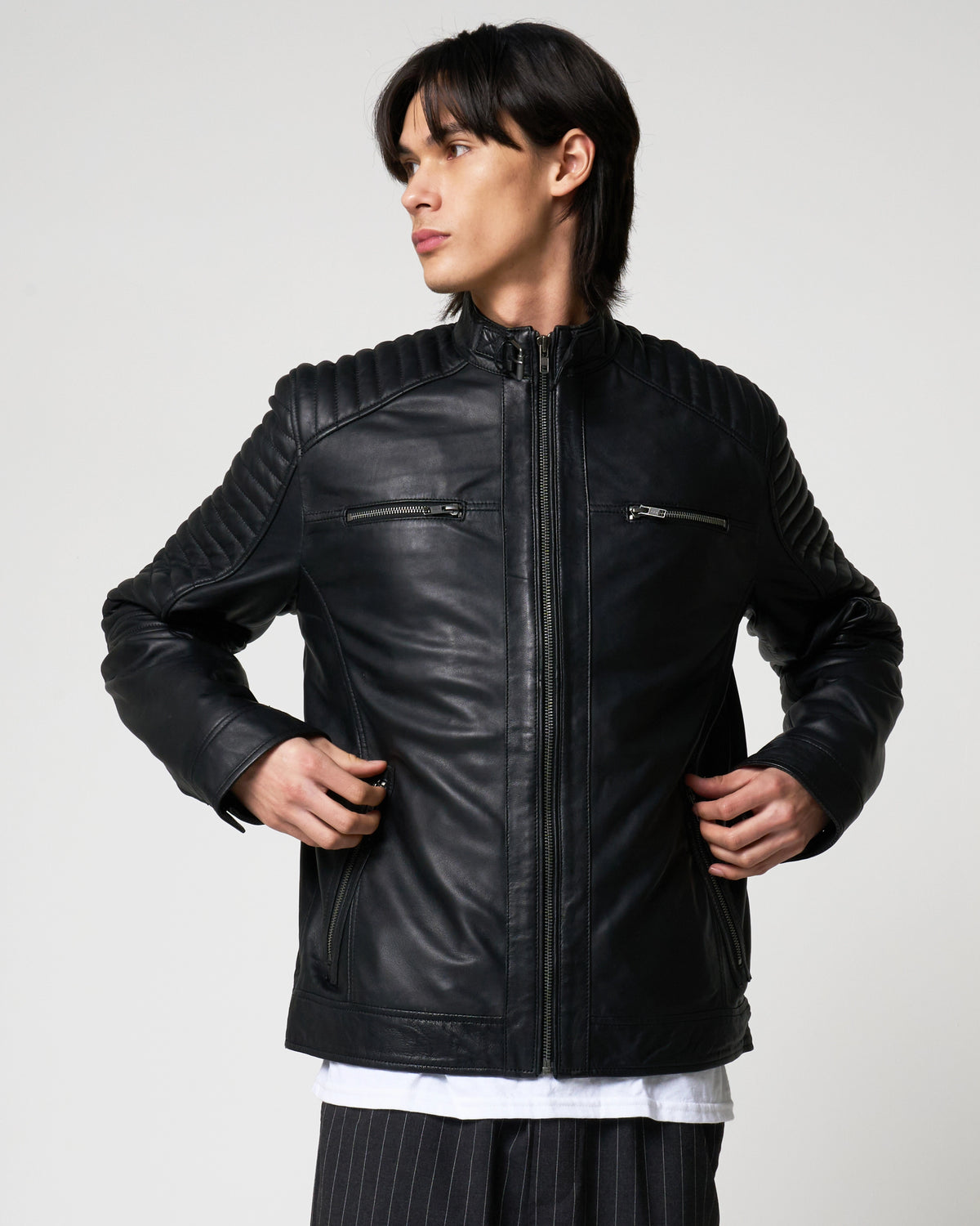Image shows a man wearing the racer jacket from Barneys Originals. The jacket has lower waist pockets and upper chest zipper pockets. The main zipline is central and the leather jacket has ribbed detail on the shoulders and sleeves.