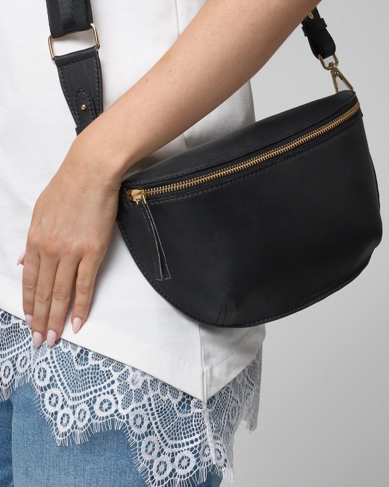 Up close image showing the leather cross body travel bag. It is black in colour and the zipper has a leather tassel.