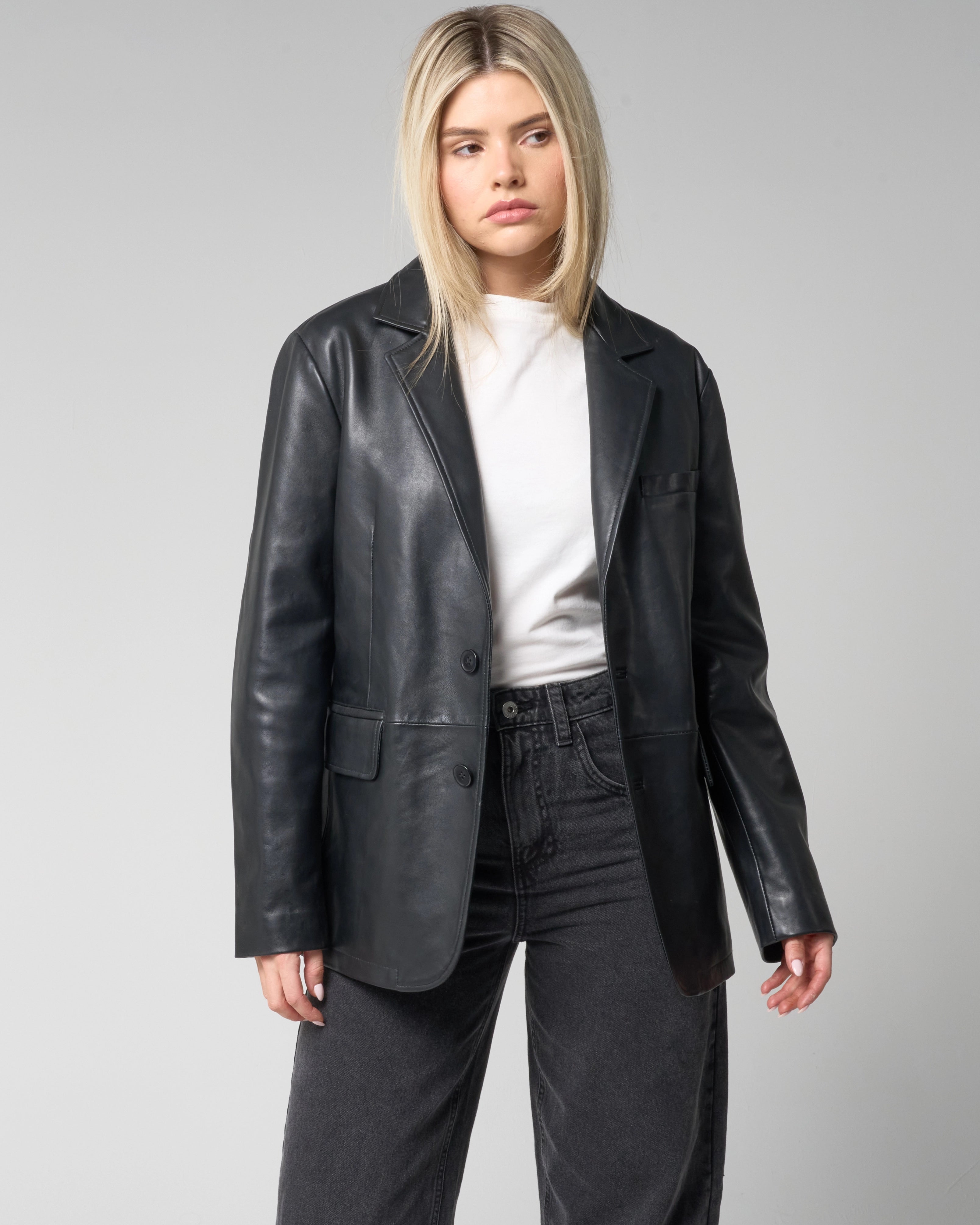 Image showing the front of the black leather blazer jacket from Barneys Originals. The jacket is worn by a woman, unbuttoned and open.