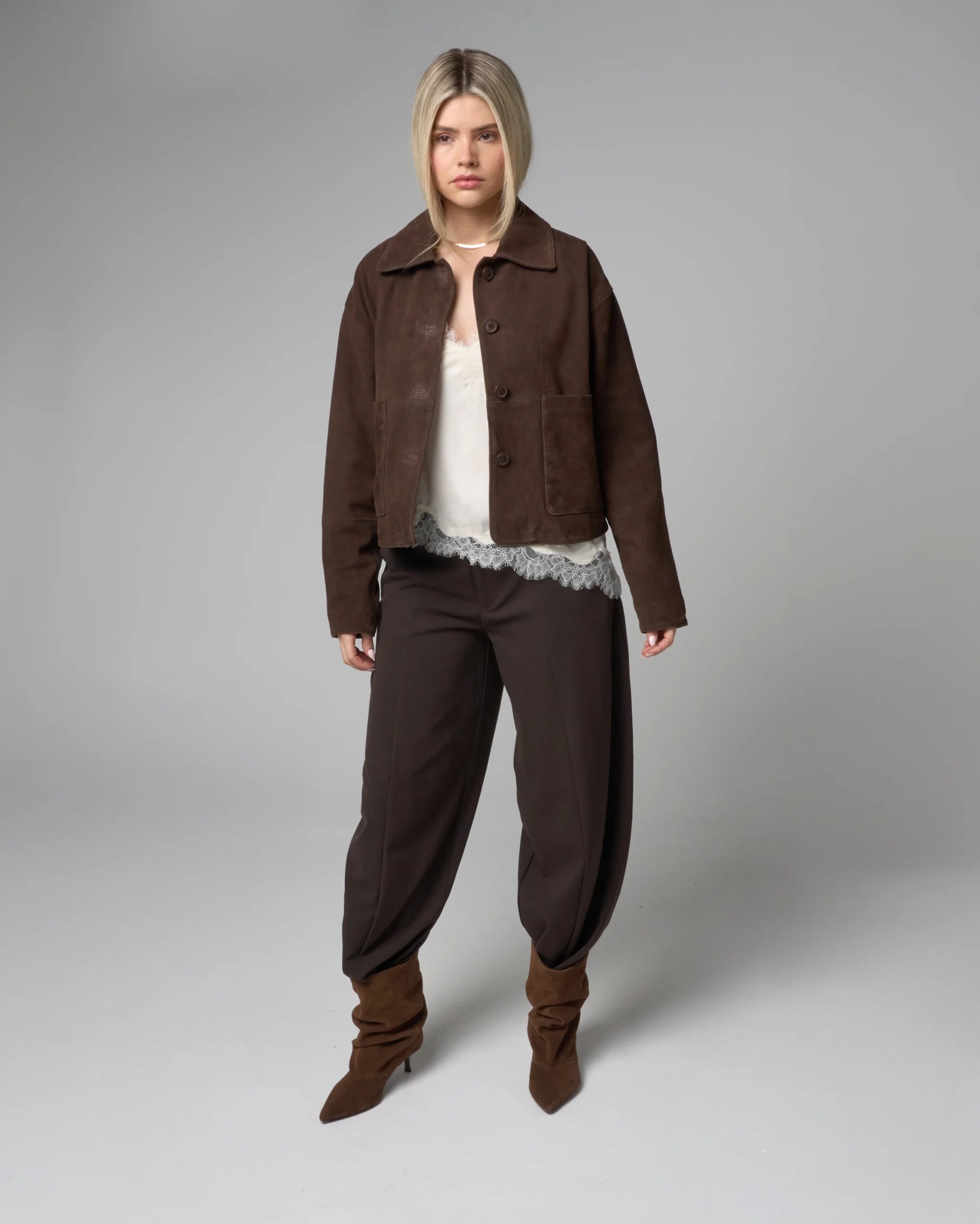 Person wearing a brown jacket and pants on a gray background
