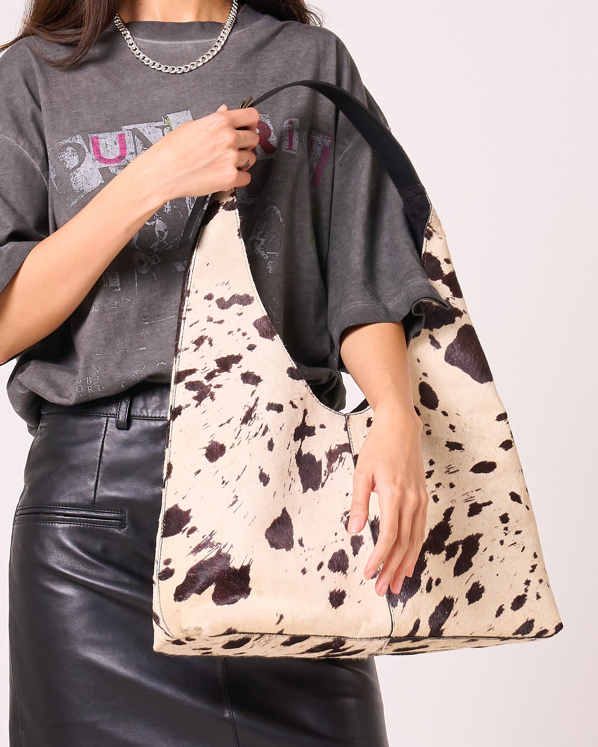Person holding a cow print bag with a plain background