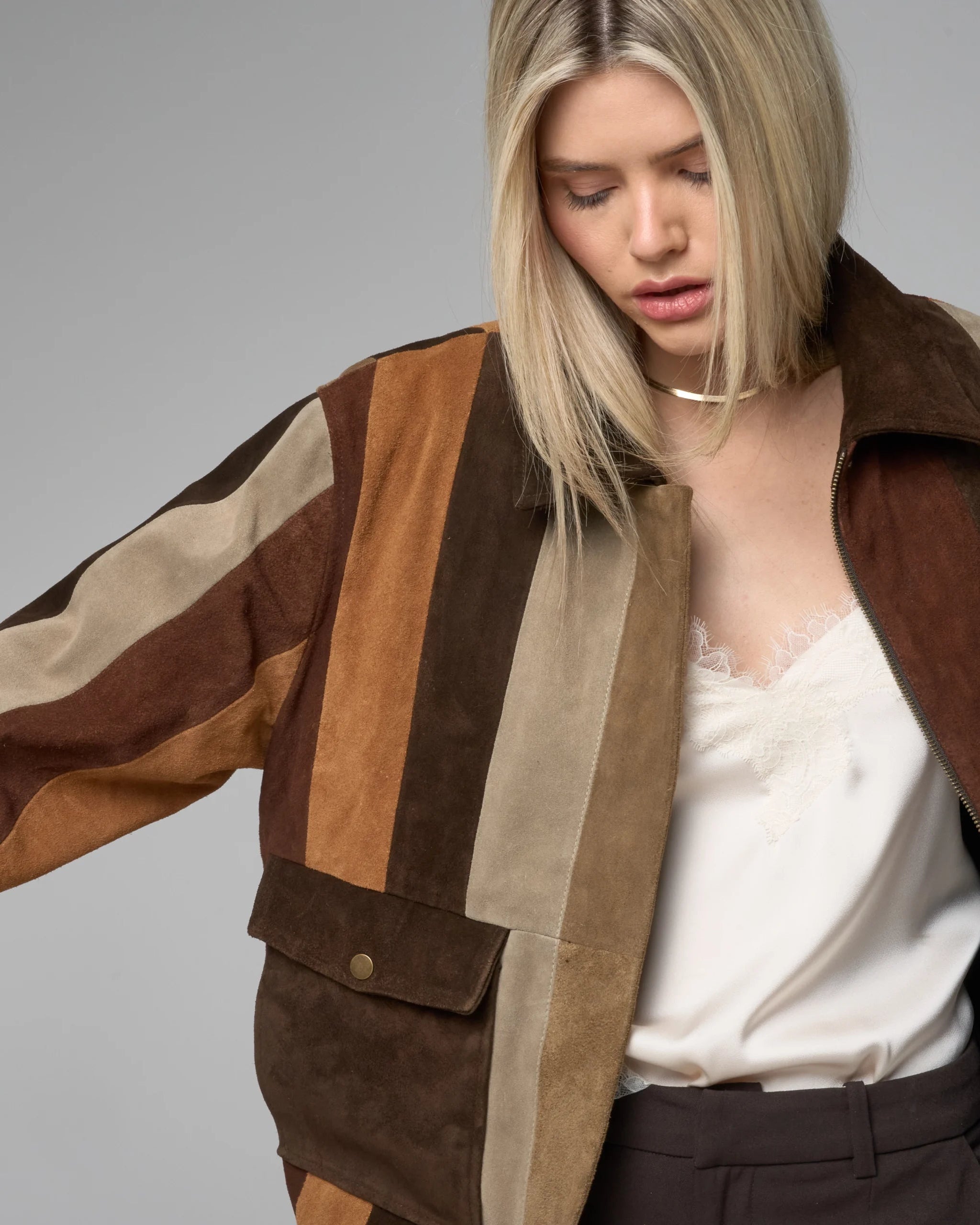 Woman wearing a brown and beige striped jacket on a gray background