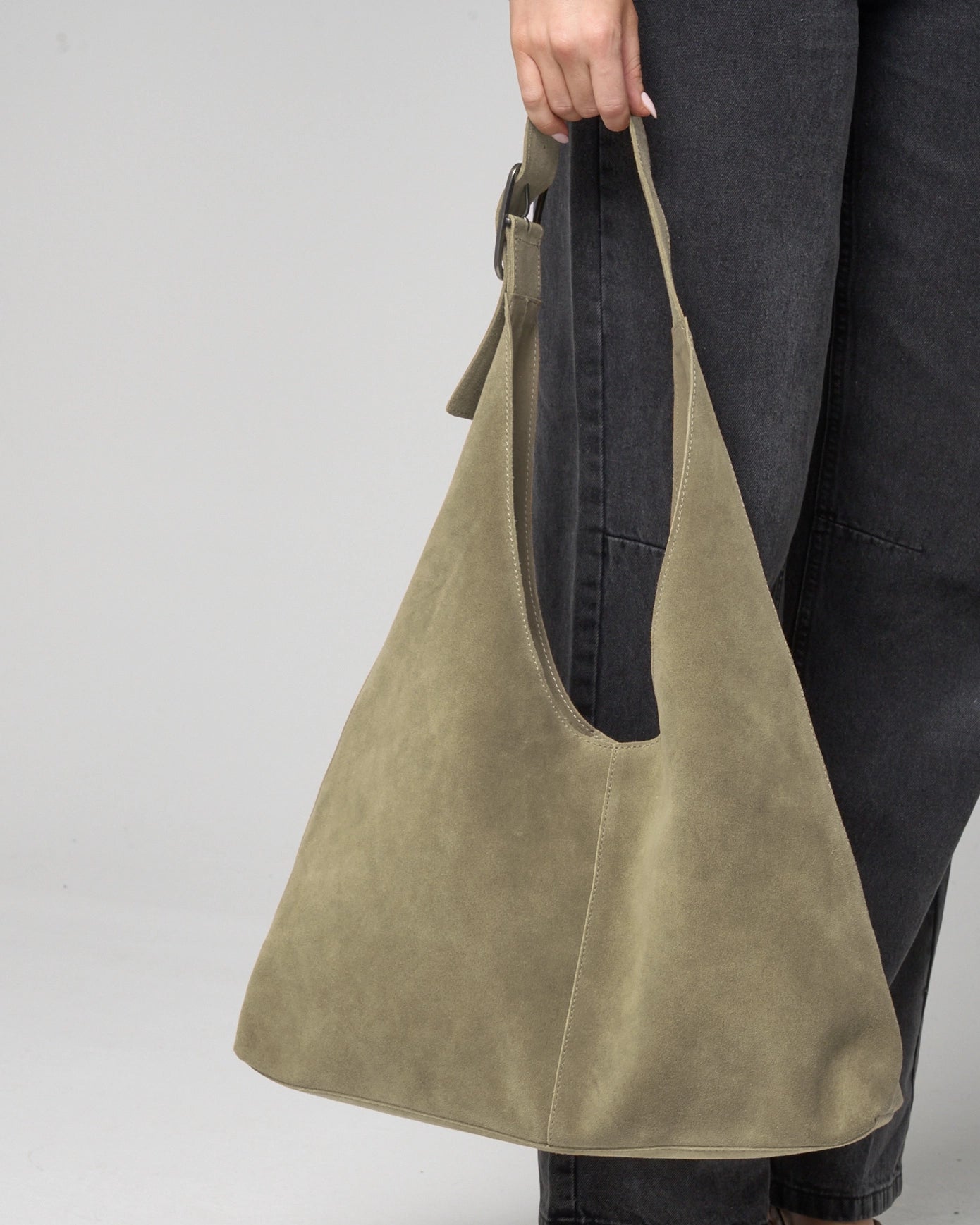 Olive coloured suede slouch bag held by woman.