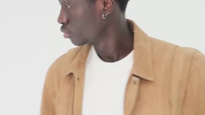Video shows cropped in footage of a photoshoot where a men wears a suede  jacket by Barneys Originals. He is modelling the item for an ecommerce shoot.