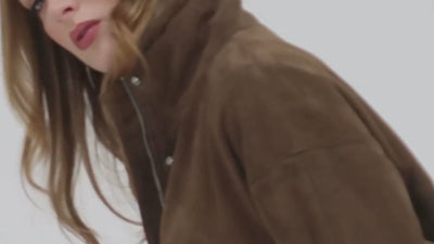 Video shows cropped in footage of a photoshoot where a woman wears a suede funnelneck jacket by Barneys Originals.