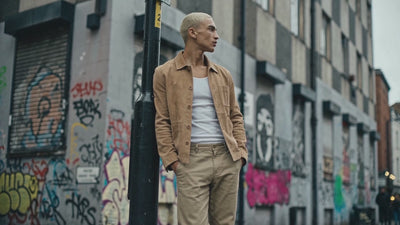 Wide frame video shows man leaning against a lamp post in Manchester Northern Quarter wearing a real suede chore jacket.