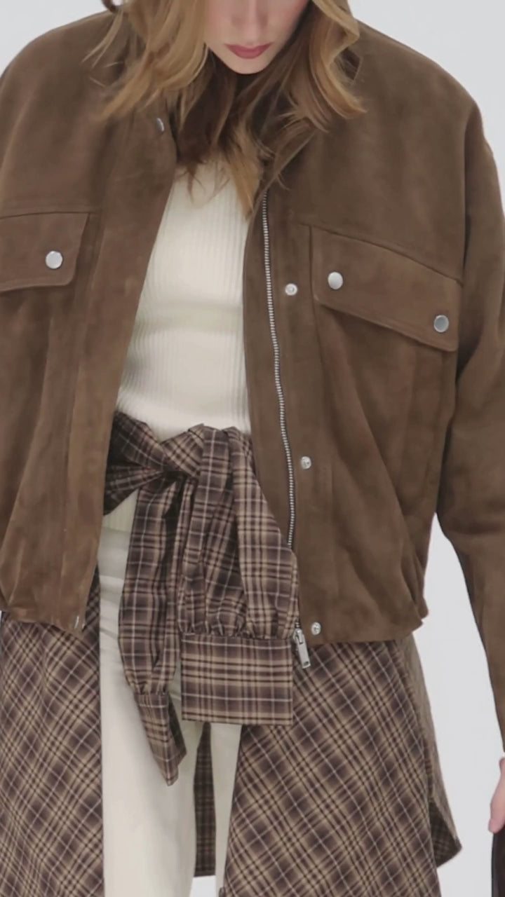 Video shows cropped in footage of a photoshoot where a woman wears a suede funnelneck jacket by Barneys Originals.