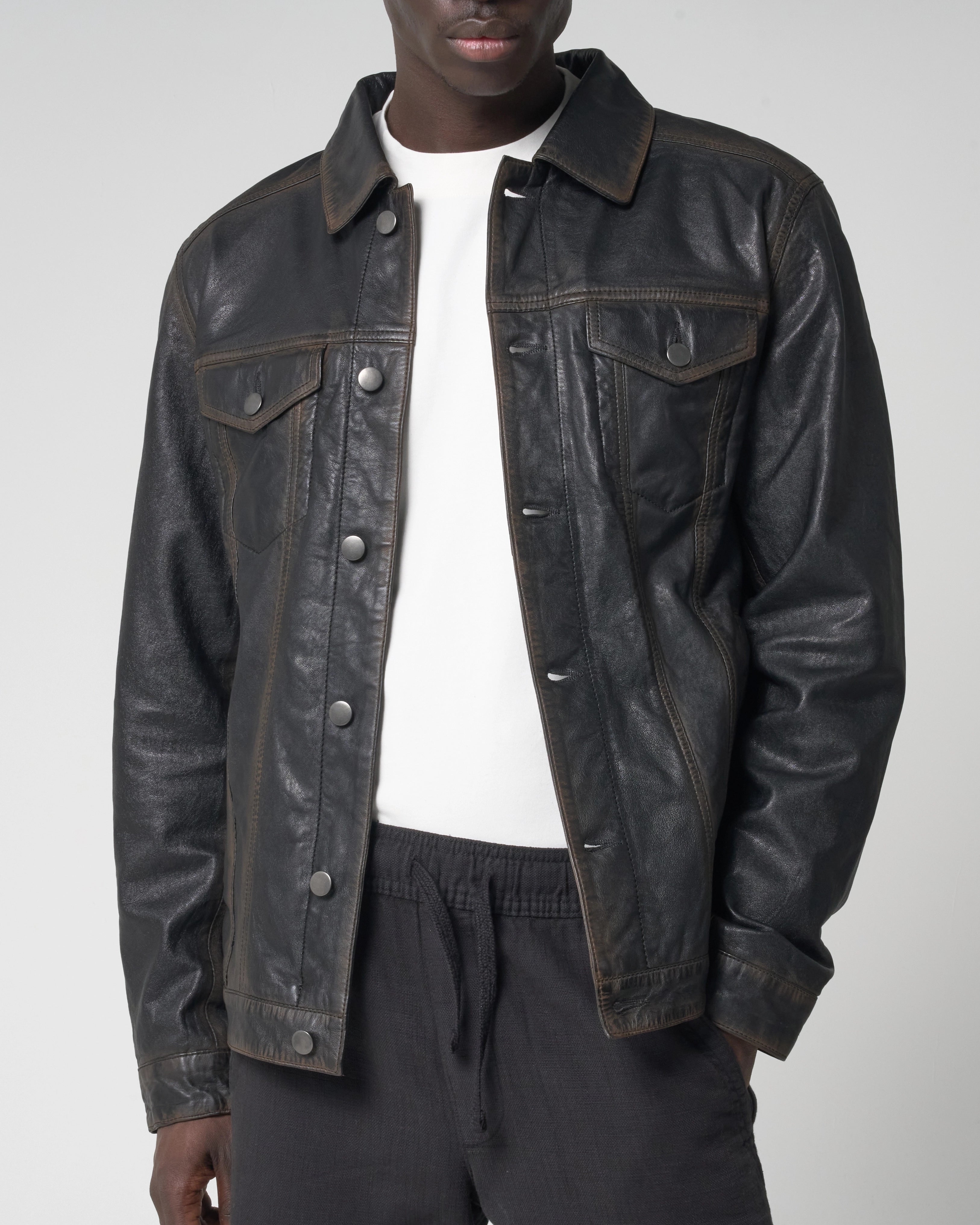 Cropped image showing the leather trucker jacket, as worn by a male model unbuttoned and open.